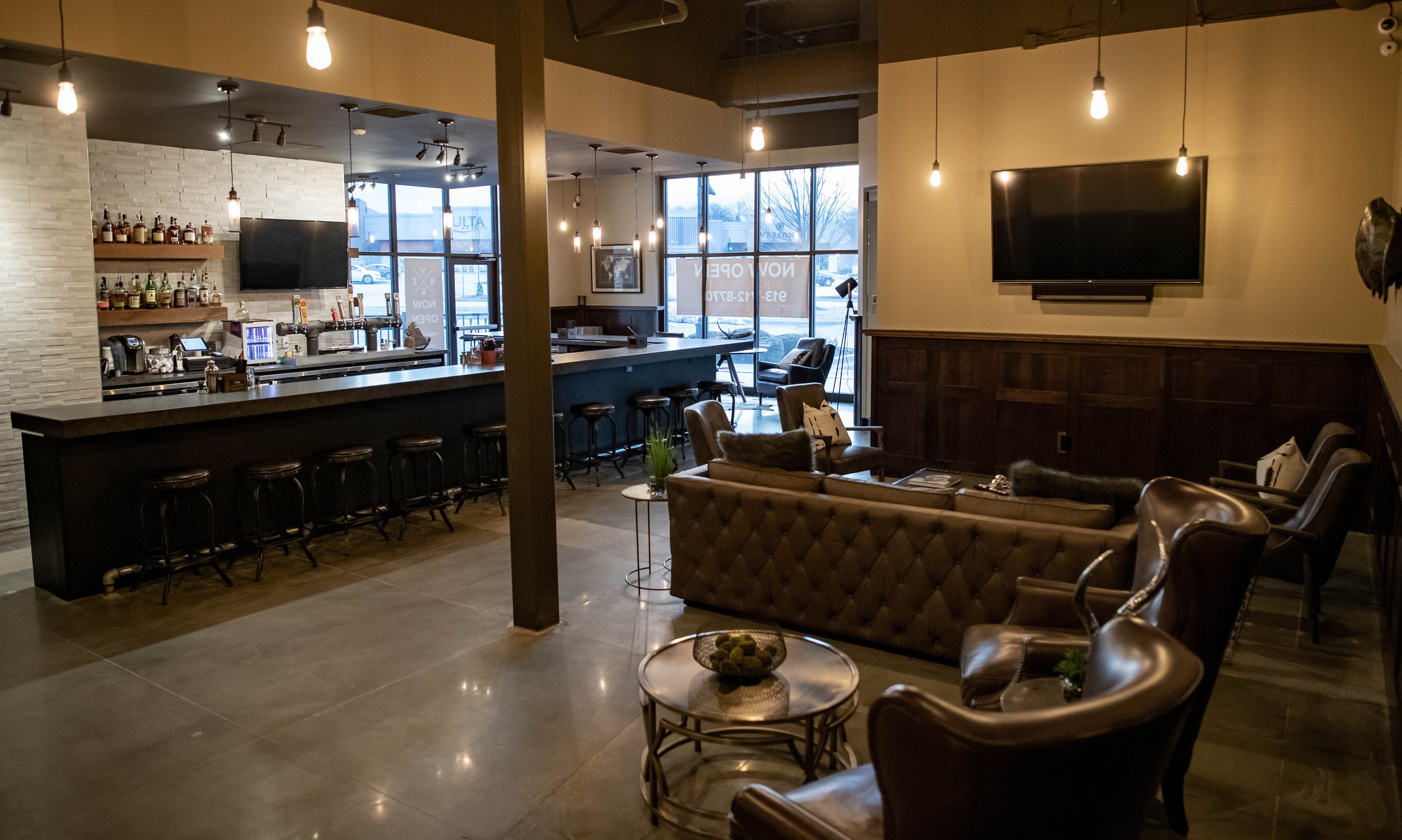 Warm Scissors & Scotch lounge with leather chairs and a long bar